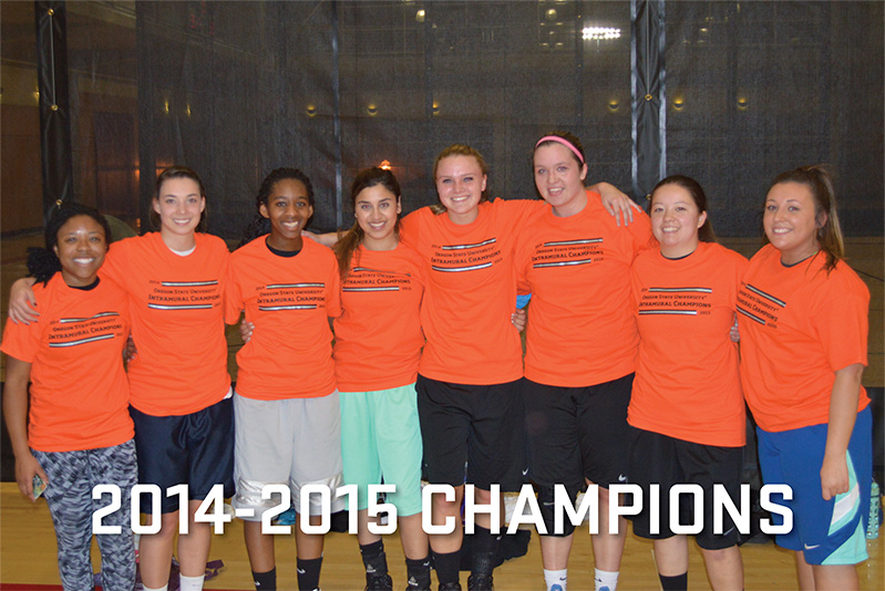 A group of women in orange champions t-shirts stand together on the basketball court.