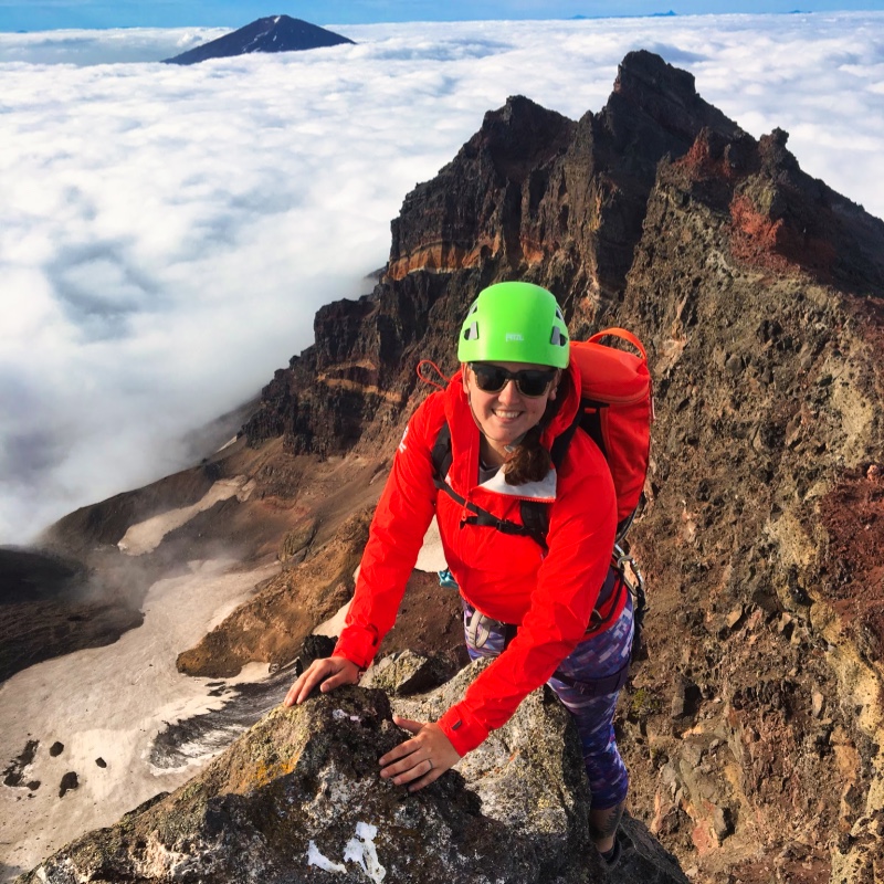 ALI Instructor Emily Abrams Perched on a Rocky Mountain Top Above the Clouds