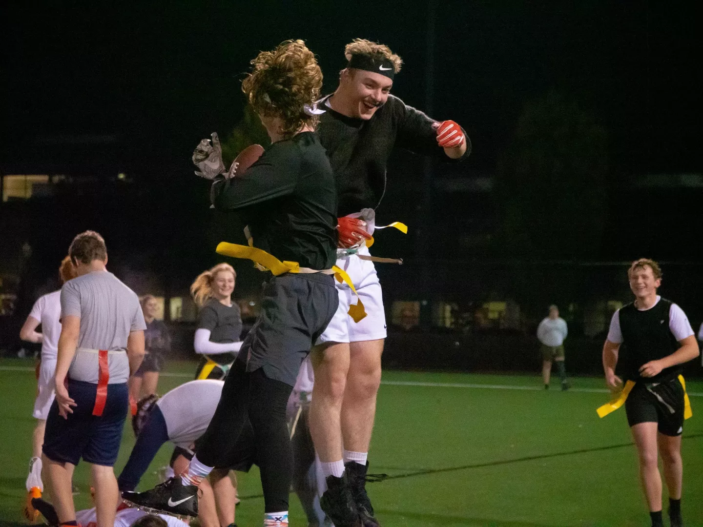 Two flag football players jump into one another in the air in celebration.