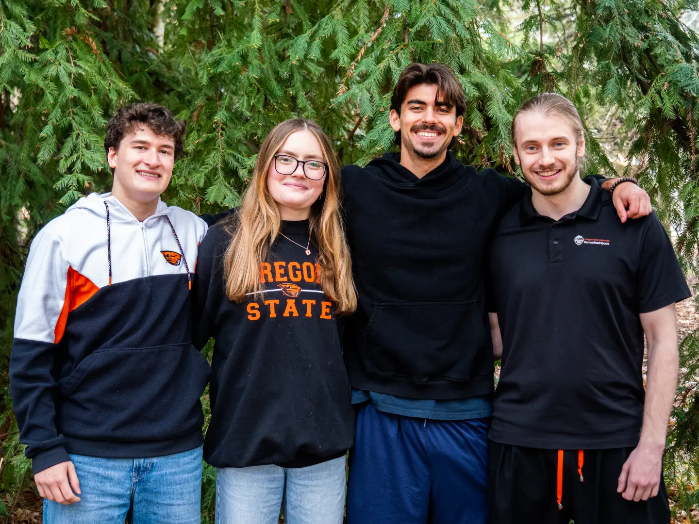Four wellness coaches stand smiling with a large green tree behind them.